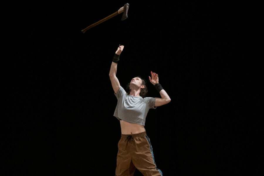 A performer reaching up towards an aerial rope.