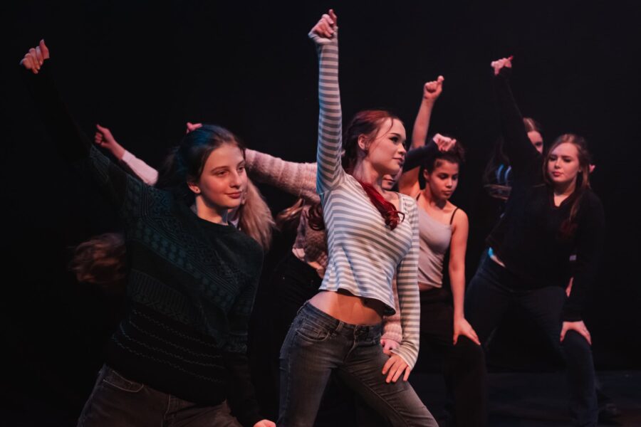 Child performers, mid-dance move, they are all posed with their hands mid-click in the air.