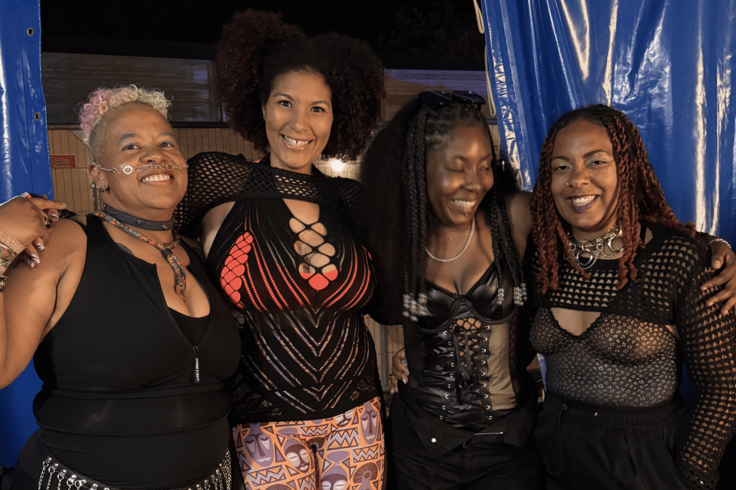 An image of 4 members of the Booty Bass collective. They are standing side by side, arms around each other and smiling