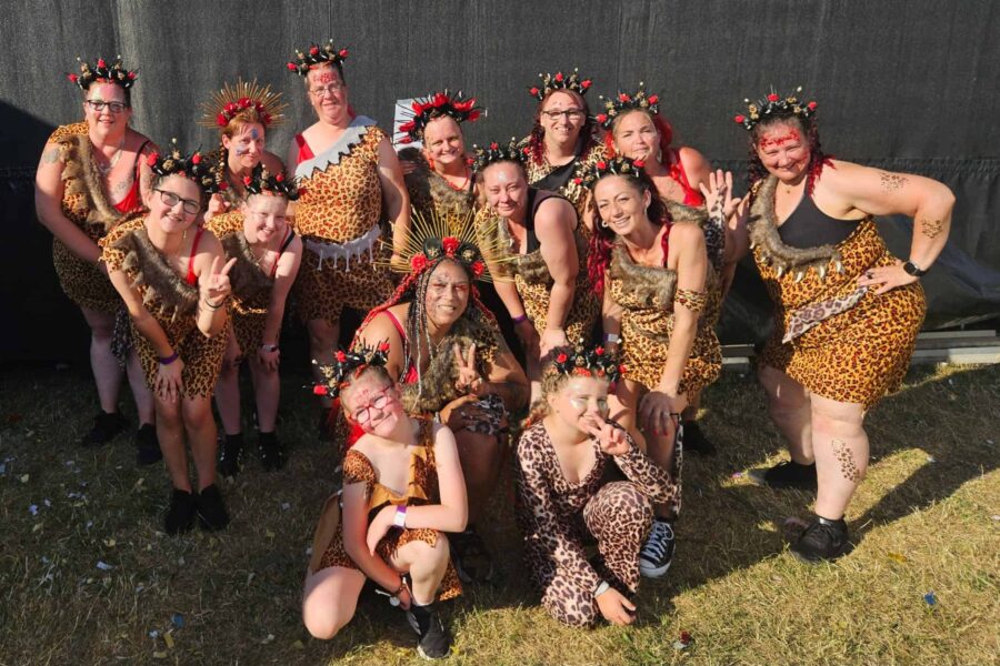 A group of perople all dresed in dance costumes with leopard print and fur covering them. They are in a gorup, posing for the picture.