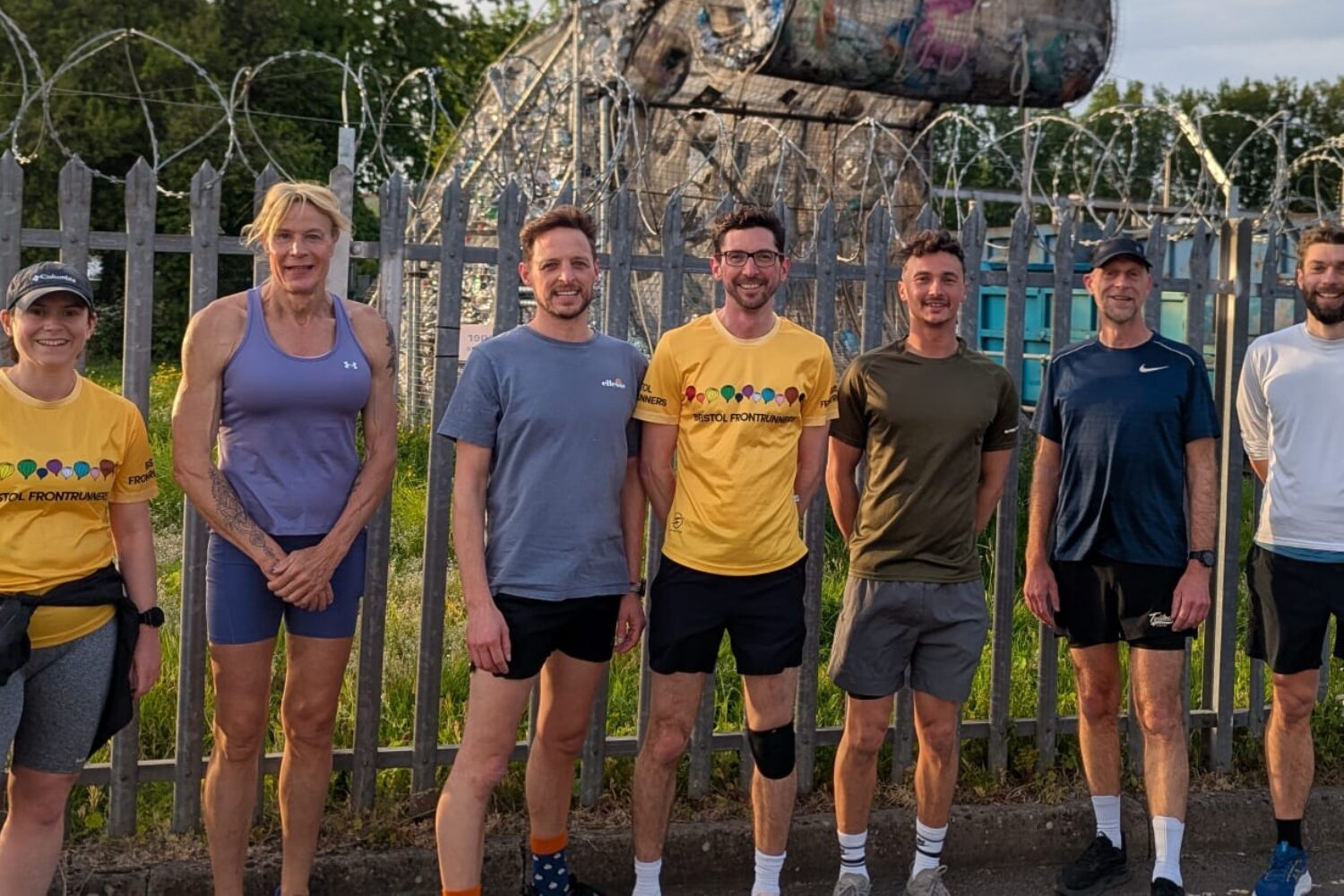 A group of runners stood outside, they are smiling at the camera.