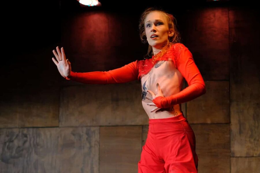 Two performers in red matching outfits of shorts and tops. One performer is being held in the air by the other.