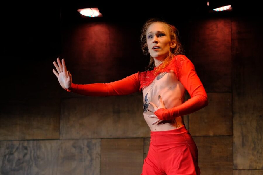 Two performers in red matching outfits of shorts and tops. One performer is being held in the air by the other.