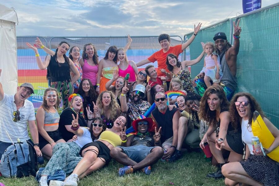 A group of people posed for the photo, they are relaxed, and some are posed lying on the floor, they are smiling and doing peace signs with their hands.