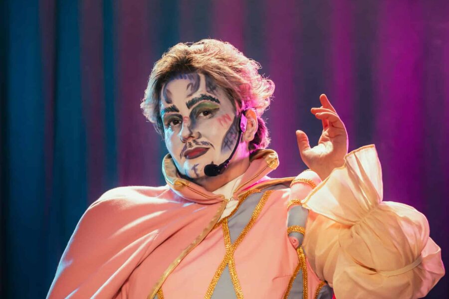 Image of Flux. Hey are wearing a pink and blue harlequin style outfit with a rather fetching pink cape.